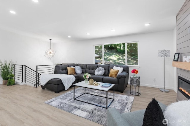 living room featuring a notable chandelier, a fireplace, recessed lighting, wood finished floors, and baseboards