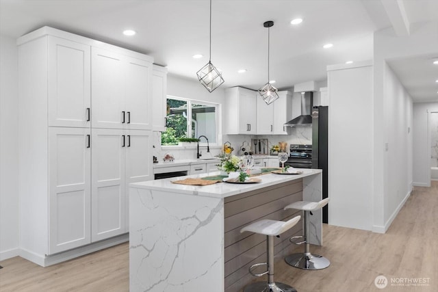 kitchen with electric stove, a breakfast bar area, tasteful backsplash, white cabinets, and wall chimney range hood