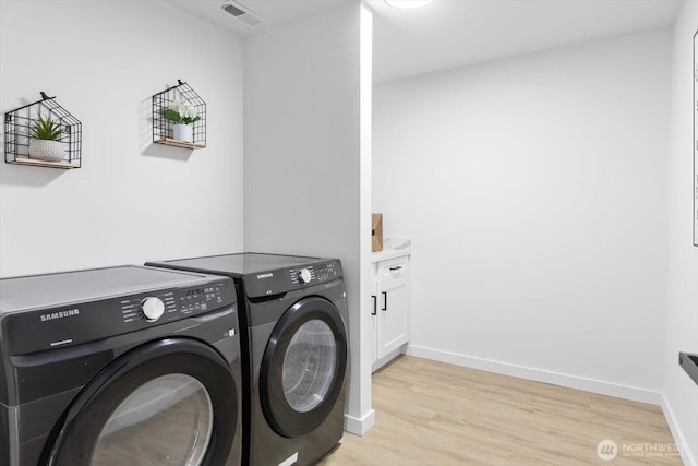 laundry room featuring light wood-style flooring, visible vents, baseboards, cabinet space, and washer and clothes dryer