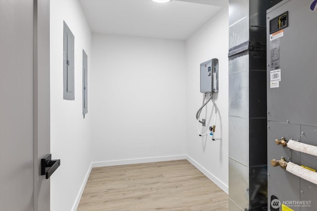 interior space featuring heating unit, wood finished floors, electric panel, and baseboards