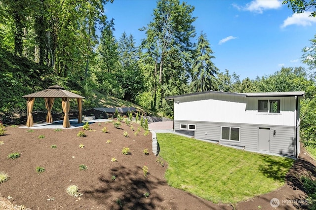 rear view of property featuring a lawn and a gazebo