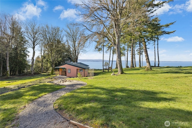 view of yard featuring a water view, driveway, and an outdoor structure