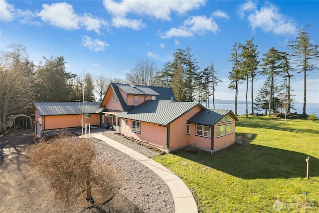 back of house featuring metal roof, a yard, and driveway