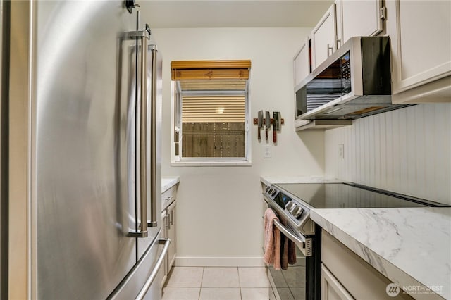 kitchen featuring light tile patterned floors, stainless steel appliances, baseboards, and light countertops