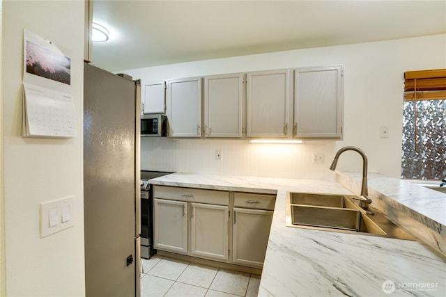 kitchen featuring a sink, stainless steel appliances, light stone countertops, and light tile patterned flooring