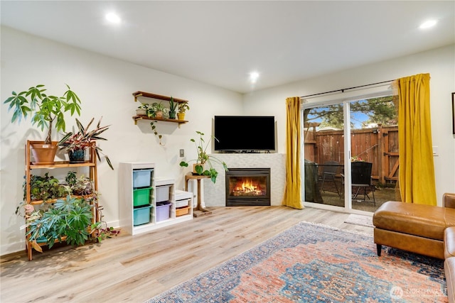 living area featuring a glass covered fireplace, wood finished floors, and recessed lighting