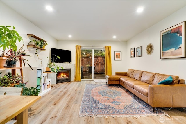 living room featuring a glass covered fireplace, wood finished floors, and recessed lighting