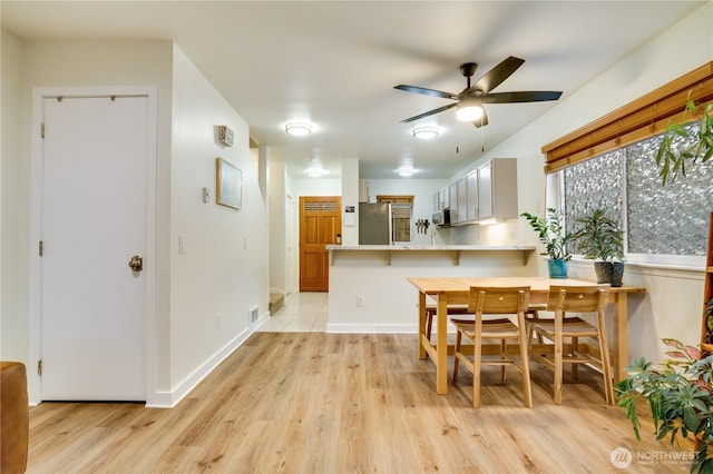 dining area with visible vents, baseboards, light wood finished floors, and ceiling fan