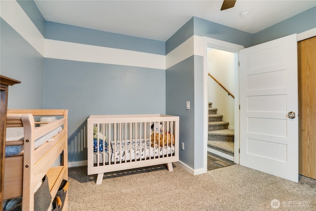 bedroom with a crib, baseboards, carpet floors, and ceiling fan