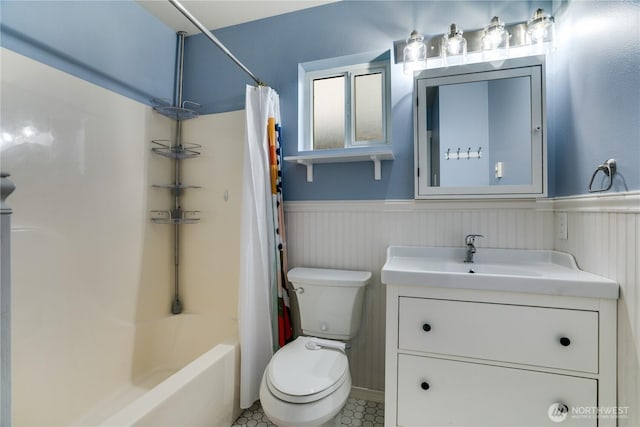 bathroom with shower / tub combo, vanity, wainscoting, and toilet