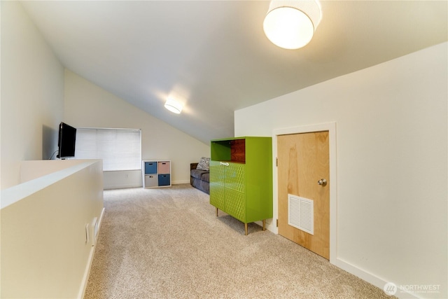 interior space with visible vents, baseboards, light colored carpet, and vaulted ceiling