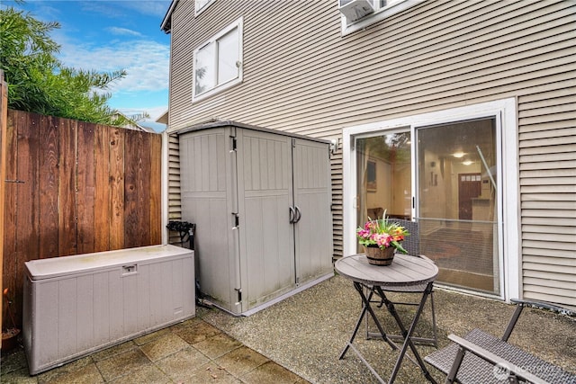 view of patio featuring a storage shed, an outdoor structure, and fence