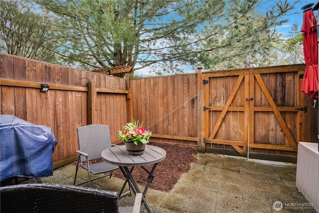 view of patio with a gate, grilling area, and fence