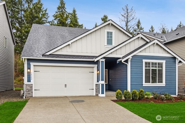 view of front of property with an attached garage, driveway, stone siding, roof with shingles, and board and batten siding