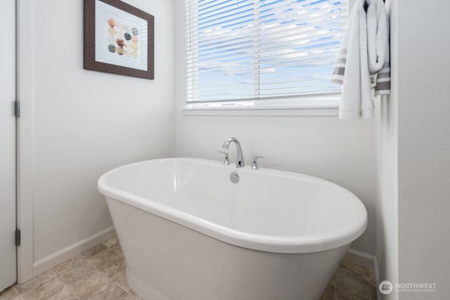 bathroom featuring tile patterned flooring, baseboards, and a freestanding bath