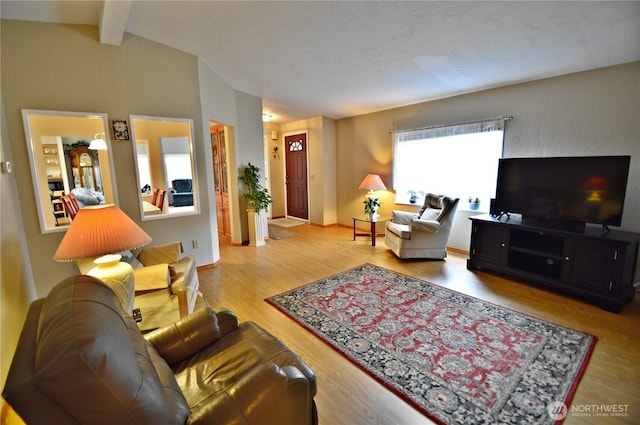 living area featuring vaulted ceiling with beams, wood finished floors, and baseboards