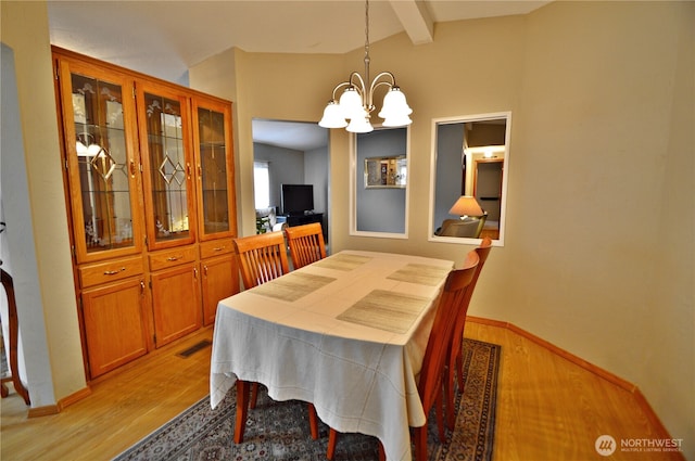 dining area with vaulted ceiling with beams, light wood finished floors, a chandelier, and visible vents