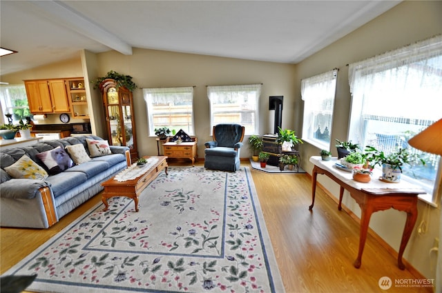 living area with lofted ceiling with beams, a healthy amount of sunlight, and light wood-style flooring