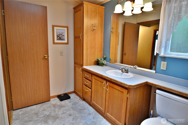 bathroom featuring baseboards, a notable chandelier, vanity, and toilet