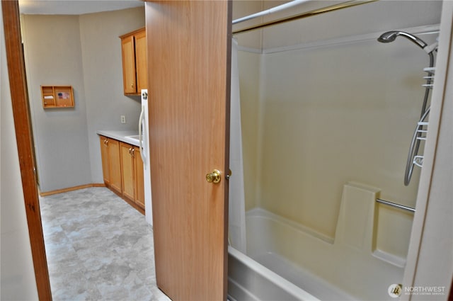 bathroom with bathing tub / shower combination, vanity, and baseboards