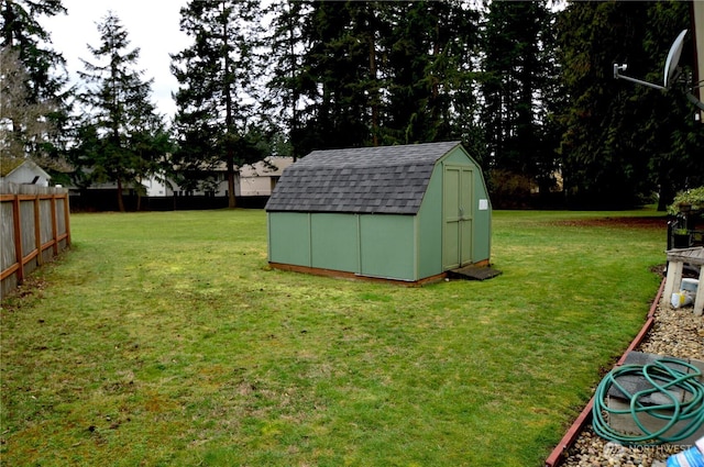 view of yard with a storage shed, fence, and an outbuilding