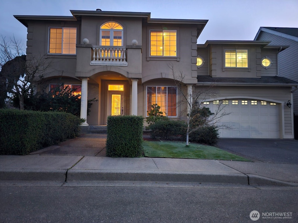 view of front of house featuring driveway, a balcony, a garage, and stucco siding