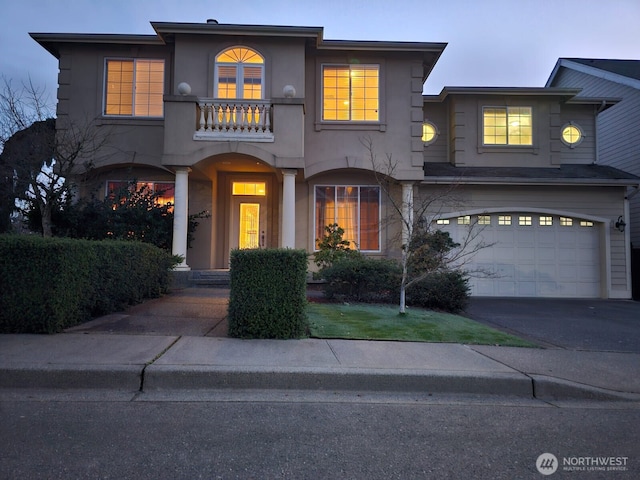 view of front of house featuring driveway, a balcony, a garage, and stucco siding