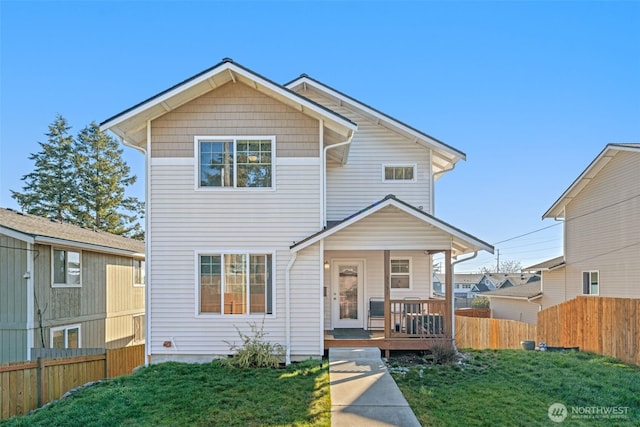 view of front facade with covered porch, fence, and a front yard