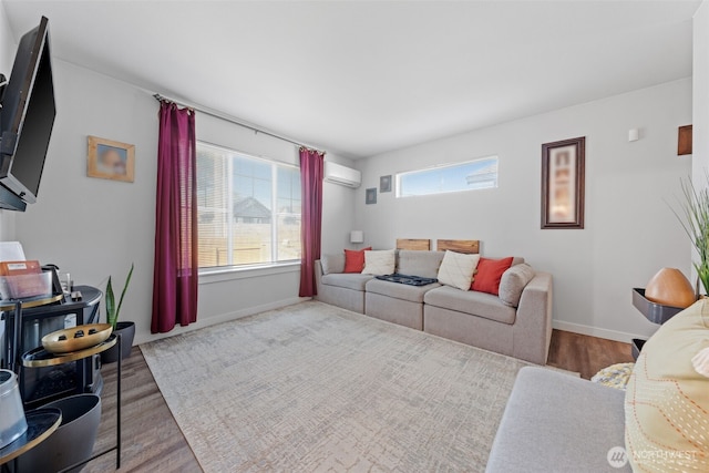 living area with a wall mounted AC, wood finished floors, and baseboards