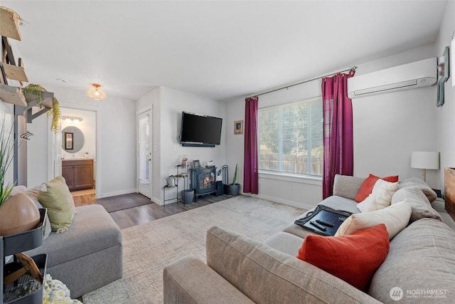 living area with a wall mounted AC, wood finished floors, a wood stove, and baseboards