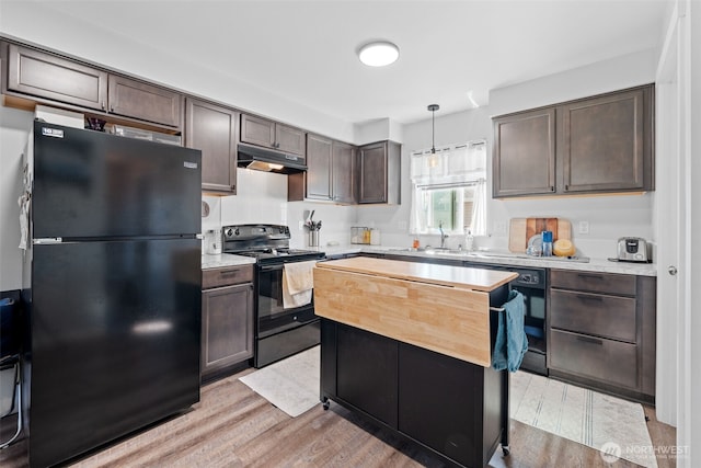 kitchen featuring light wood-style flooring, under cabinet range hood, dark brown cabinets, light countertops, and black appliances