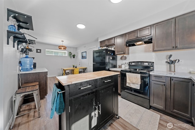 kitchen with black appliances, light wood finished floors, butcher block counters, and under cabinet range hood