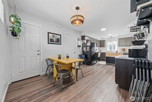 dining area featuring light wood finished floors, baseboards, and visible vents