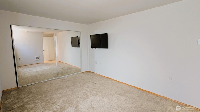 unfurnished bedroom with a closet, carpet floors, baseboards, and visible vents