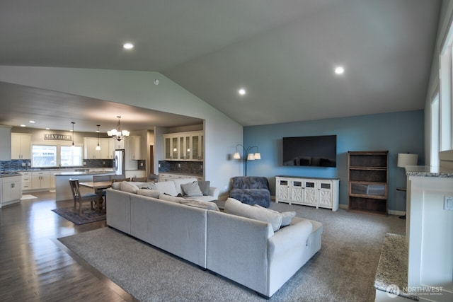 living area featuring dark wood-type flooring, lofted ceiling, a notable chandelier, and recessed lighting