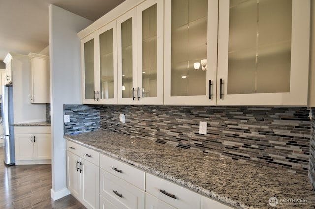 kitchen with light stone countertops, white cabinetry, dark wood-style floors, and decorative backsplash