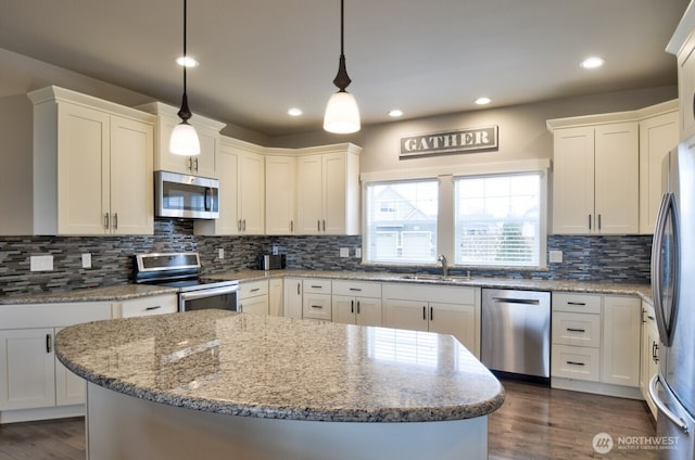 kitchen with tasteful backsplash, white cabinets, dark wood-style flooring, stainless steel appliances, and a sink