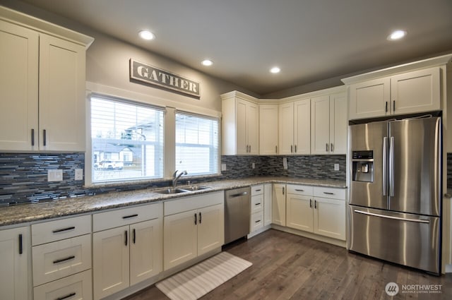 kitchen with dark wood-style floors, stainless steel appliances, tasteful backsplash, white cabinetry, and a sink