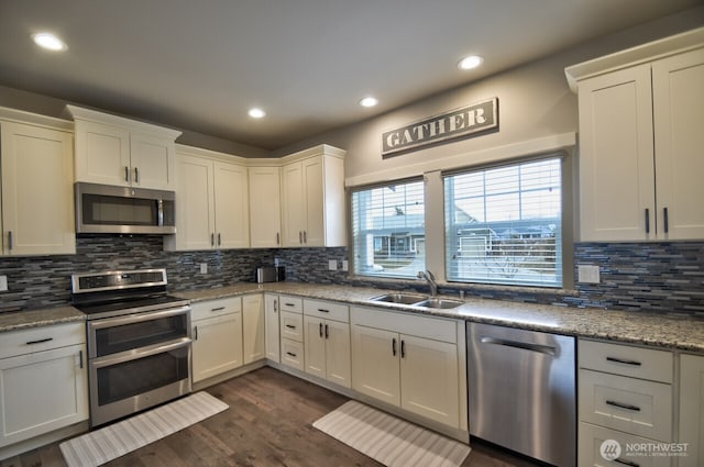 kitchen with dark wood-style floors, stainless steel appliances, a sink, and decorative backsplash