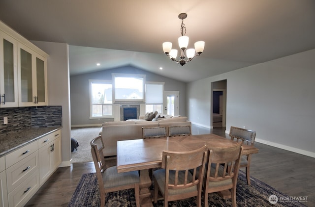 dining space with lofted ceiling, an inviting chandelier, baseboards, and dark wood-style flooring