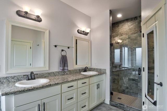 bathroom featuring double vanity, a stall shower, and a sink