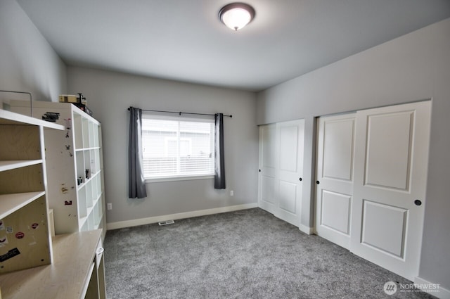 unfurnished bedroom featuring carpet flooring, two closets, and baseboards