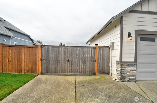 view of home's exterior featuring stone siding, a gate, fence, and board and batten siding