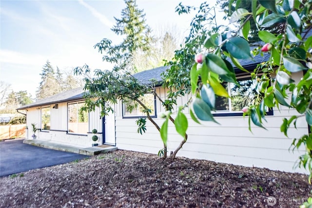 view of property exterior with a shingled roof and fence