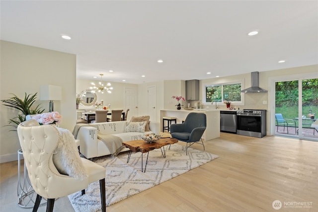 living room with light wood-style floors, a notable chandelier, and recessed lighting