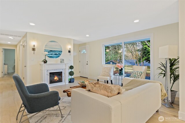 living room with light wood-style floors, recessed lighting, and a high end fireplace