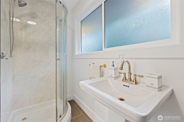 bathroom with a stall shower and a sink