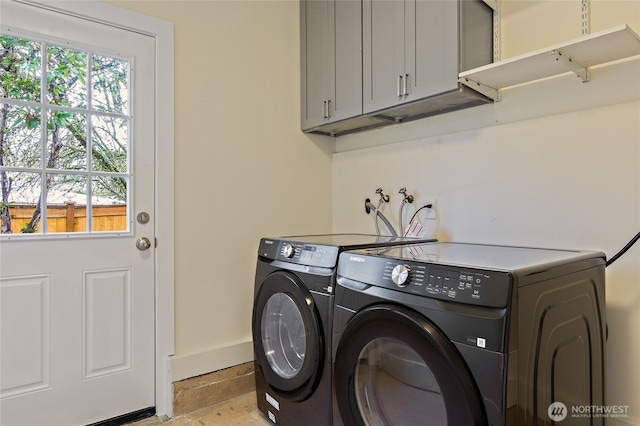 washroom featuring cabinet space, baseboards, and washing machine and clothes dryer