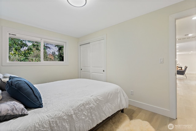 bedroom featuring a closet, light wood-type flooring, visible vents, and baseboards