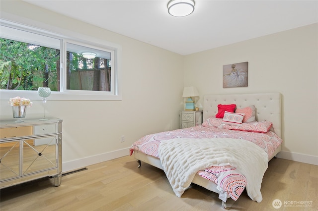 bedroom with wood finished floors, visible vents, and baseboards